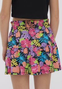 Gonna floreale con sfondo nero e motivi multicolori di fiori e foglie, vita arricciata e orlo a volant.