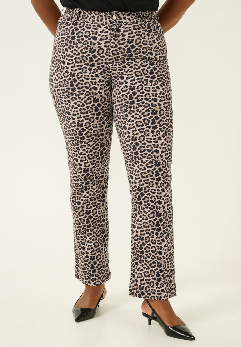 Pantalons imprimés léopard en beige et marron foncé, présentant un design à jambe droite et une texture lisse, associés à des escarpins noirs à bout pointu.