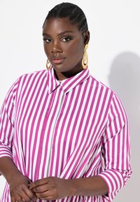 Camicia a righe rosa e bianche con design a bottoni, colletto e maniche a tre quarti. Tessuto morbido e vestibilità casual.