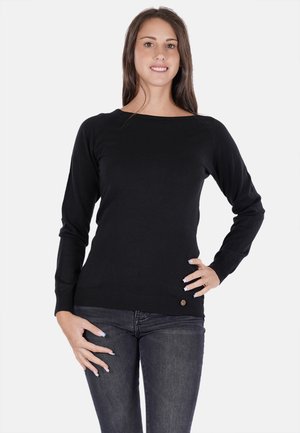 Maglione nero a maglia con maniche lunghe, scollo ampio, polsini aderenti e un piccolo dettaglio con logo all'orlo, indossato con jeans scuri.
