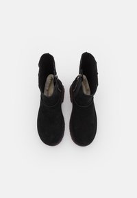 Paire de bottines en daim noir avec doublure intérieure en fourrure et fermetures éclair latérales, vues de dessus sur fond blanc.