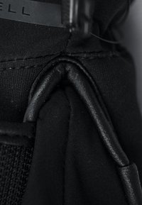 Primo piano di una borsa in tessuto nero con superficie testurizzata, caratterizzata da un accento in pelle nera e dettagli di cucitura lungo il bordo.