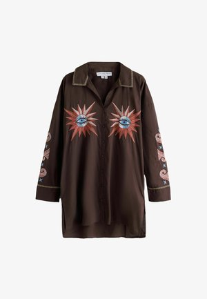 Chemise marron foncé à boutons avec col, présentant des motifs brodés de rayons de soleil avec des yeux bleus sur la poitrine et des motifs tourbillonnants avec des étoiles sur les manches.