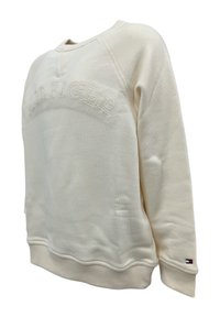 Felpa color crema con logo ricamato "TOMMY HILFIGER". Caratterizzata da polsini e orlo a costine, con un piccolo accento del logo sulla manica.