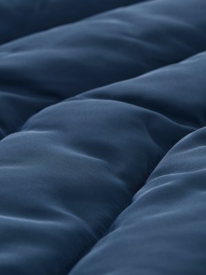 Gros plan sur un tissu matelassé bleu foncé lisse avec des coutures douces et arrondies créant des sections rembourrées surélevées.