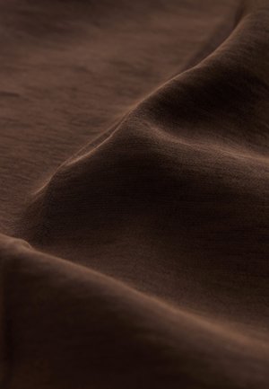 Tessuto marrone con trama particolare, che mostra dolci onde e una sottile lucentezza. Il materiale appare morbido, leggero e finemente tessuto.