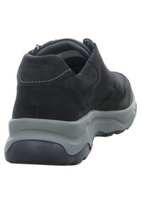 Black leather shoe with grey rubber sole. Features streamlined design, rounded shape, and contrasting stitching on the back.
