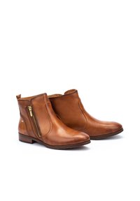 Botas de tobillo de cuero marrón con textura suave, con cremallera lateral, punta redondeada y tacón bajo apilado.