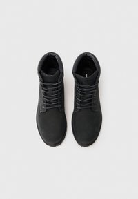 Botas negras hasta el tobillo, hechas de cuero suave con punteras redondas, que cuentan con cordones y detalles de costura en contraste a lo largo de los costados.