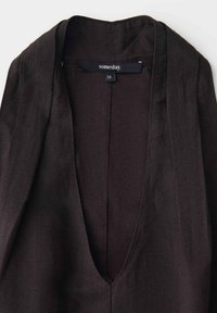 Blazer en lin brun foncé avec col en V profond et étiquette de marque "someday." indiquant la taille 36 à l'intérieur de l'encolure.