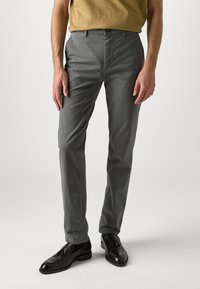 Grijze katoenen broek met een rechte snit, voorzien van een knoop- en ritssluiting. Gecombineerd met zwarte instappers, die een gladde textuur en een perfecte pasvorm laten zien.
