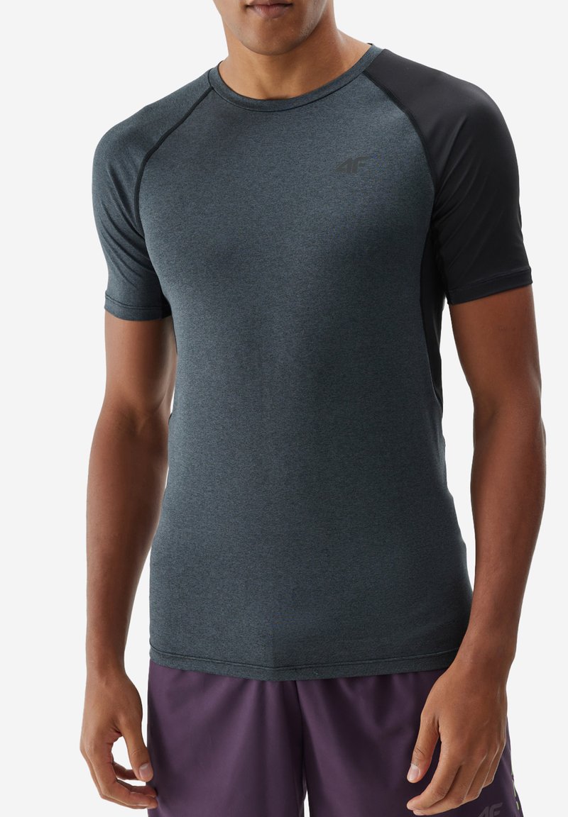 Ciemnoszara koszulka sportowa z krótkimi rękawami raglanowymi, wykonana z gładkiego materiału. Posiada subtelne logo na klatce piersiowej oraz kontrastowe czarne panele na ramionach.