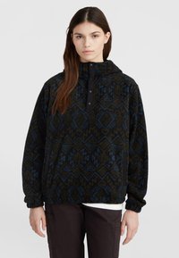 Pull en polaire vert foncé avec des motifs géométriques bleus et noirs. Il dispose d'un col montant, de boutons-pression et de poignets élastiques.