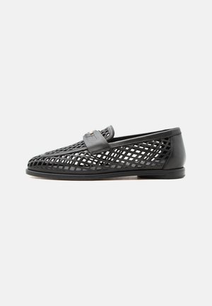 Mocassino in pelle nera con design a rete aperta e cinturino in pelle sulla parte superiore, su uno sfondo chiaro e uniforme.