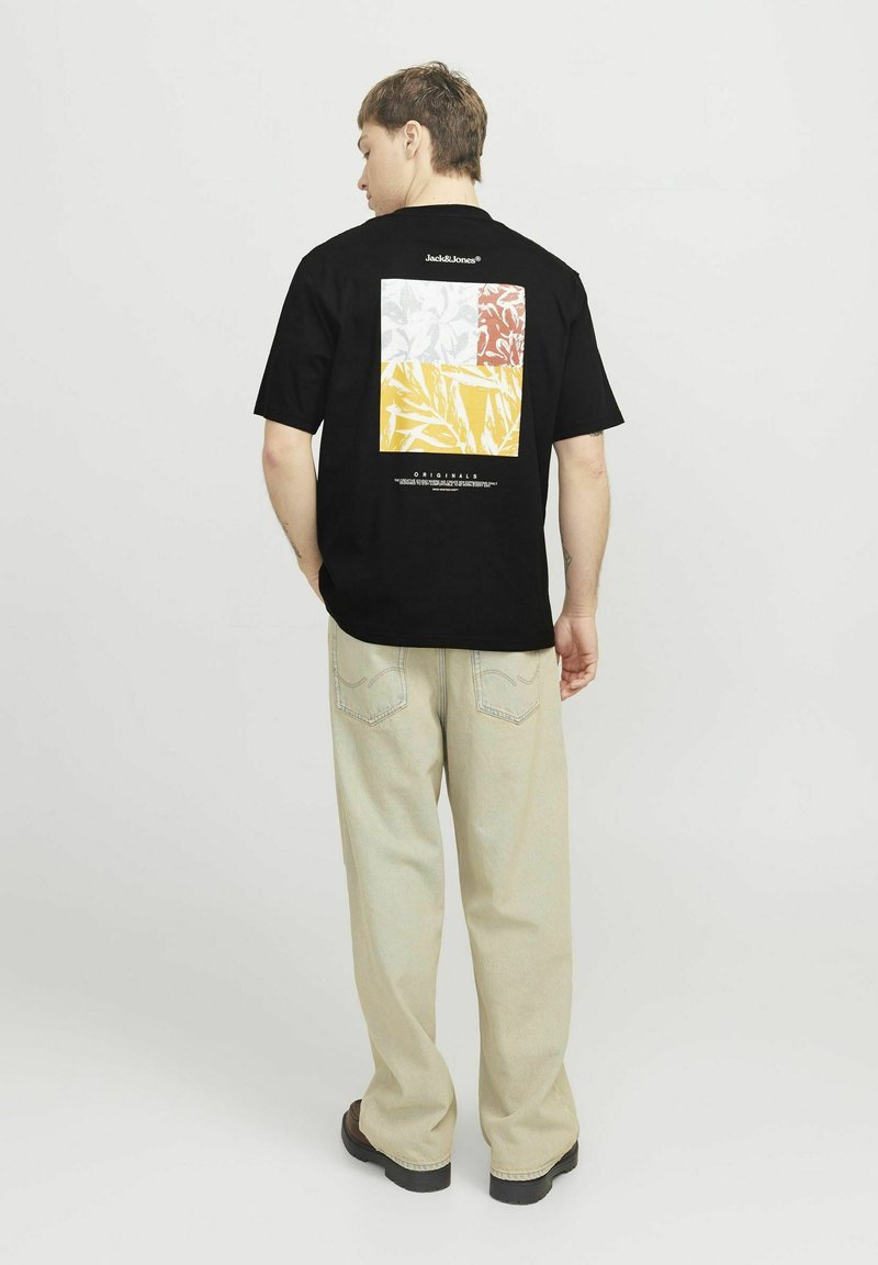 Sort T-shirt med et farverigt grafik med fire sektioner i gul, hvid, rød og et blomstermønster på ryggen. Afslappet pasform.