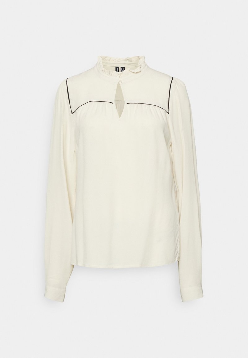 Blouse blanche à manches longues avec col à volants, encolure en forme de goutte et détail de passepoil noir sur la poitrine et les épaules.