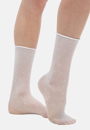 Chaussettes blanches transparentes à la cheville avec de petits pois, dotées d'un poignet blanc contrastant, d'une texture lisse et d'une forme ajustée.