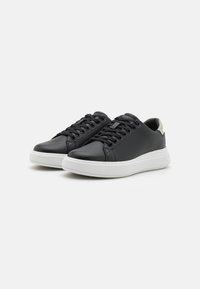 Baskets en cuir noir avec semelle en caoutchouc blanche, bout arrondi et design à lacets, présentant une accentuation de talon gris clair contrastant.