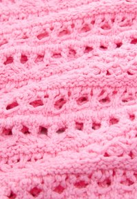 Pink knitted fabric featuring an open lace pattern with textured ridges and loops, creating a lightweight and detailed surface.