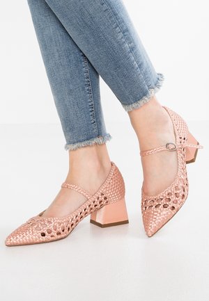 Różowe plecione buty na obcasie z ostrym noskiem, wyposażone w pasek wokół kostki i szeroki obcas. Tekstura jest pleciona; gładkie pastelowe wykończenie podkreśla design.