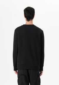 Schwarzer Sweatshirt aus weichem Stoff, mit Rundhalsausschnitt, gerippten Bündchen und Saum. Einfaches Design ohne sichtbare Logos oder Muster.