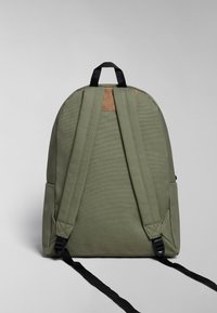 Zelený plátěný batoh s černými polstrovanými popruhy a hněd�ým koženým akcentem nahoře. Má zaoblený tvar a boční kapsy.