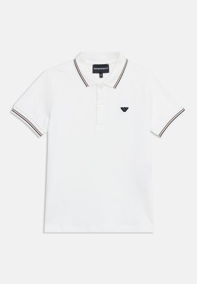 Polo blanc à manches courtes avec col et poignets rayés noir et marron, patte de boutonnage à deux boutons, et petit logo noir sur la poitrine gauche.