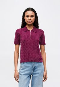 Lühikese varrukaga, tõmbluku sulgemisega polo särk sügava lilla tekstuuriga kangast, millel on teemantmuster; kaeluse detail ja mugav lõige. Sobib hästi helesiniste teksadega.