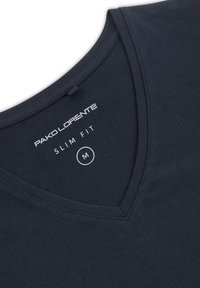 Obcisła, granatowa koszulka typu v-neck wykonana z miękkiej bawełny. Zawiera metkę z napisem "PAKO LORENTE", "SLIM FIT" oraz rozmiar "M" nadrukowany wewnątrz okolicy kołnierza.