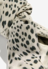 Texturált bézs szövet sötét foltokkal, részletes kidolgozással, puha, gyűrt mintával, amely kiegészítők számára alkalmas.