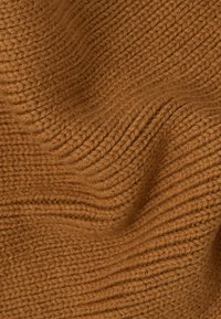 Gebreide stof in een gedempte bruine kleur met een textuur en geribbelde patronen. Het materiaal lijkt zacht en licht pluizig, wat de warmte en diepte benadrukt.
