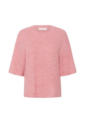 Kvinde står iført en fluffy lyserød kortærmet sweater, mørkeblå højttaljede jeans med sort bælte og leopardmønstrede flade sko.