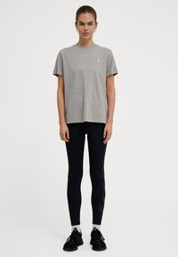 Herre grå bomulds t-shirt med korte ærmer, samlet med sorte leggings med sidelister og sorte træningssko med hvide detaljer.
