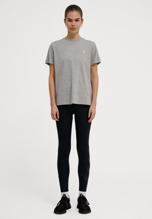 Herre grå bomulds t-shirt med korte ærmer, samlet med sorte leggings med sidelister og sorte træningssko med hvide detaljer.