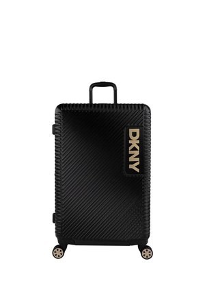Maleta rígida negra con surcos diagonales, asa retráctil y cuatro ruedas. Presenta un logo dorado de DKNY en el bolsillo lateral.