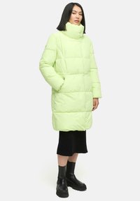 Lichtgroene pufferjas met een hoge kraag, oversized pasvorm en groot quiltpatroon. Voorzien van zijzakken en een gladde, glanzende textuur.