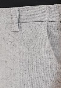 Szczotkowane szare spodnie z tkaniny mają fakturowany splot z delikatnymi czarnymi kropeczkami, pętelkami na pasek oraz są dopasowane z przednimi kieszeniami.