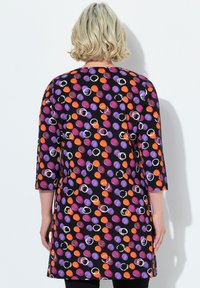 Dreiviertelarm-Tunika in Schwarz mit einem mehrfarbigen Punktmuster in Lila, Orange und Weiß. Hergestellt aus weichem Stoff mit einer lässigen Passform.