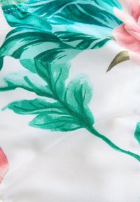 Cvetlična tkanina z rožnatimi cvetovi in zelenimi listi na belem ozadju. Material je videti gladek s satenskim zaključkom.