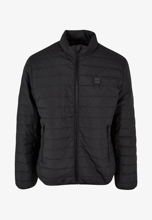 Veste noire matelassée avec un col montant, fermeture éclair intégrale et poches latérales zippées. Texture lisse avec un motif de couture horizontal.