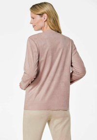 Langärmliges Oberteil aus weichem, hellrosa Material mit glatter Textur. Gerader Schnitt, runder Ausschnitt und minimales Design ohne sichtbare Beschläge.