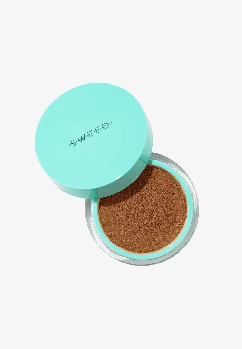 Poudre bronzante libre dans un contenant transparent avec un couvercle vert menthe. La poudre est d'une teinte brune chaude avec une texture fine.