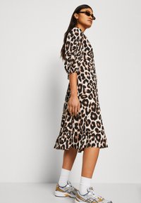 Leopardprint midi-kjole med utringet kant, puffede ærmer og blødt stof. Kombineret med sølv- og guldsneakers samt hvide sokker.