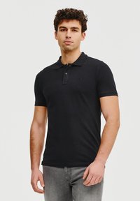 Czarna koszulka polo wykonana z bawełny, z klasycznym ko�łnierzykiem, zapięciem na trzy guziki i krótkimi rękawami. Dyskretny logo na piersi.