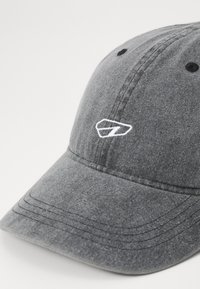 Gray cotton baseball cap with a rounded crown, curved brim, and stitched detailing. Features a white embroidered logo on the front.