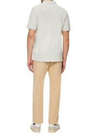 Lichte grijze polo met korte mouwen, gecombineerd met beige broek en witte sneakers. Gladde textuur, klassiek kraagontwerp.