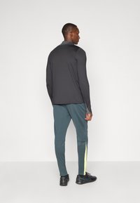 Černé dlouhé rukávy, slim fit; tyrkysové kalhoty se žlutými bočními pruhy; černé sportovní boty; hladká, lehká látka.