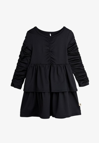 Črna dolga obleka z dolgimi rokavi, z nabrano dekoracijo, večplastnim krilom in okroglim izrezom. Narejena iz mehke, raztegljive tkanine.