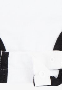 Material alb cu accente negre zimțate. Dispune de închideri cu capse și o textură moale. Design simplu cu detalii de culoare contrastante.