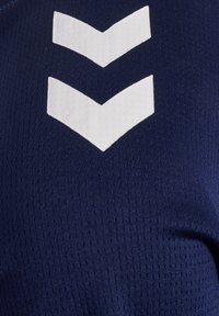 Two white downward chevron stripes on textured dark blue fabric, likely part of a sports jersey or athletic wear.